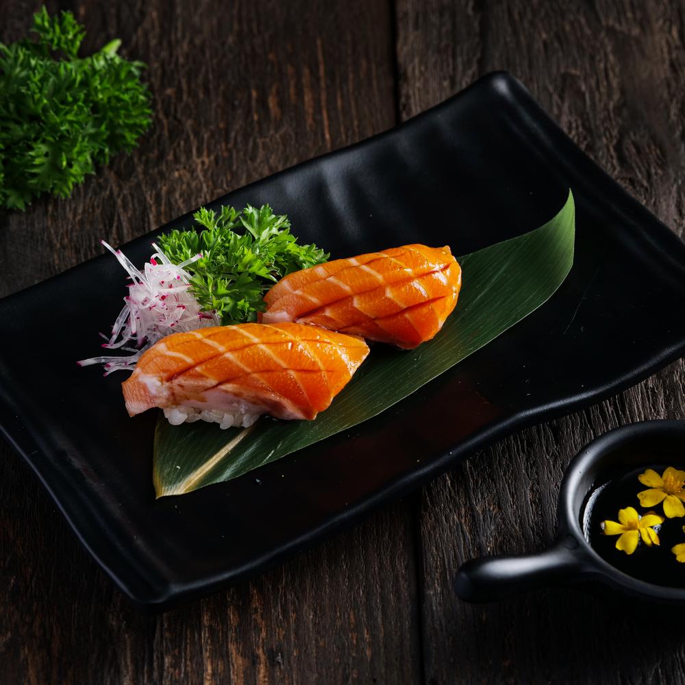 Salmon nigiri sushi served on a traditional wooden platter at Jo Sushi Bar.